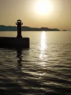 燈塔、夕陽與海面上的金色波浪