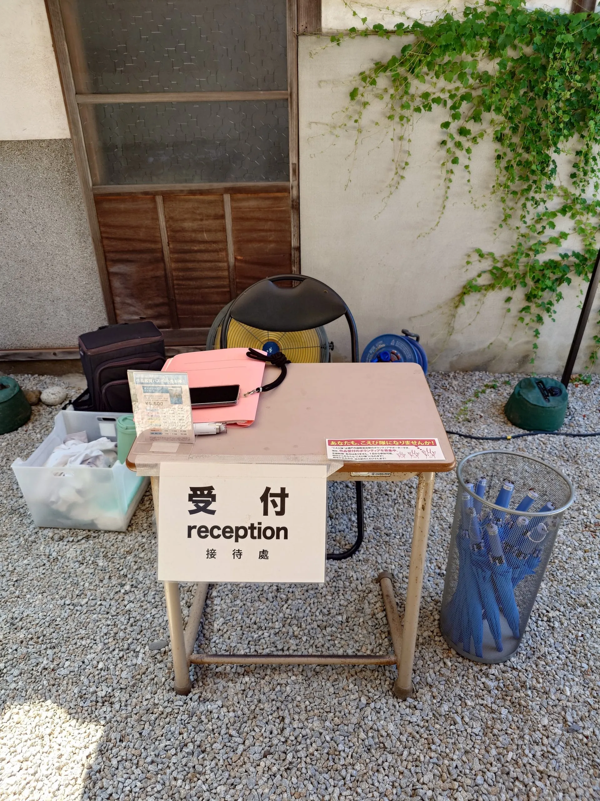「部屋の中の部屋」的接待處，椅子後面是工業扇，旁邊的箱子裡有降溫噴霧、防蟲噴霧等用品，桌子旁籃子裡的雨傘供旅客使用